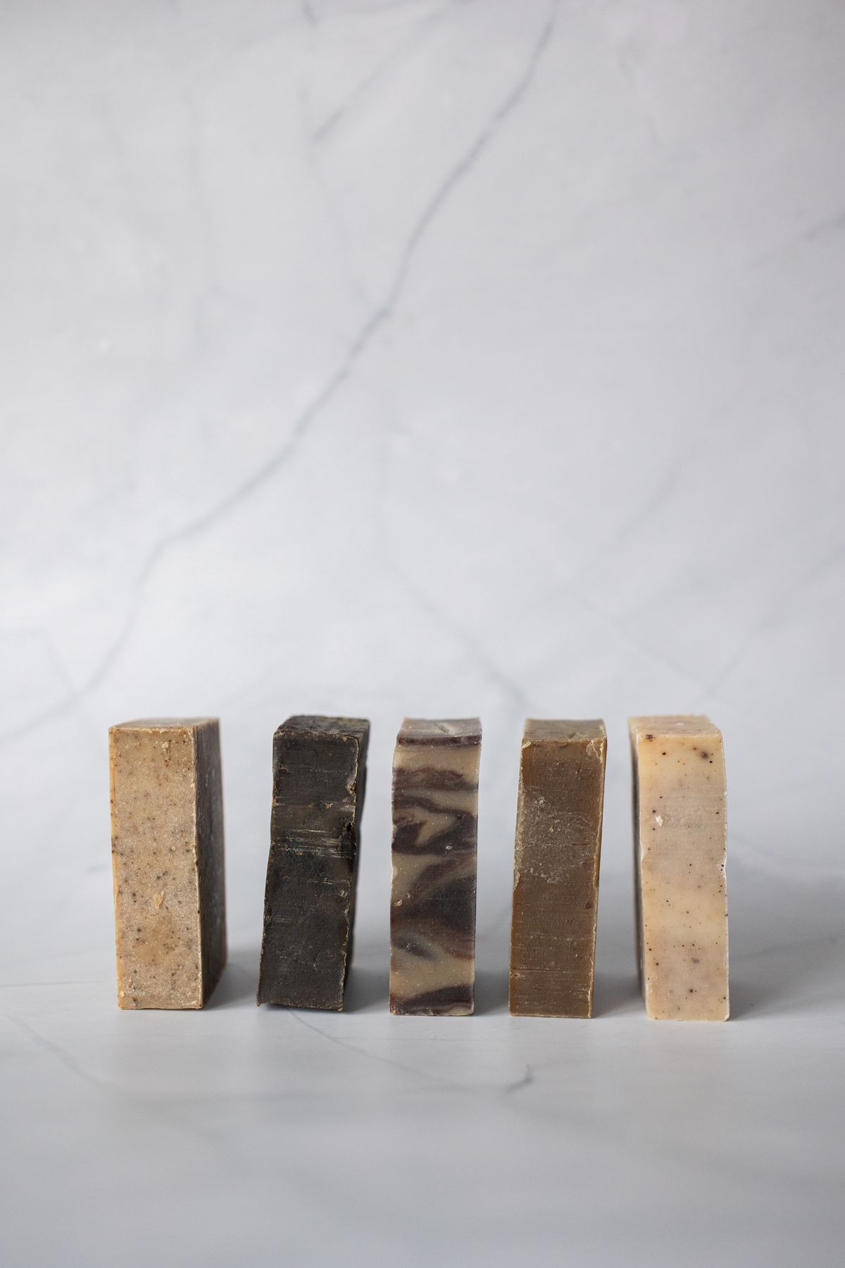 Five natural handmade soap bars standing on marble