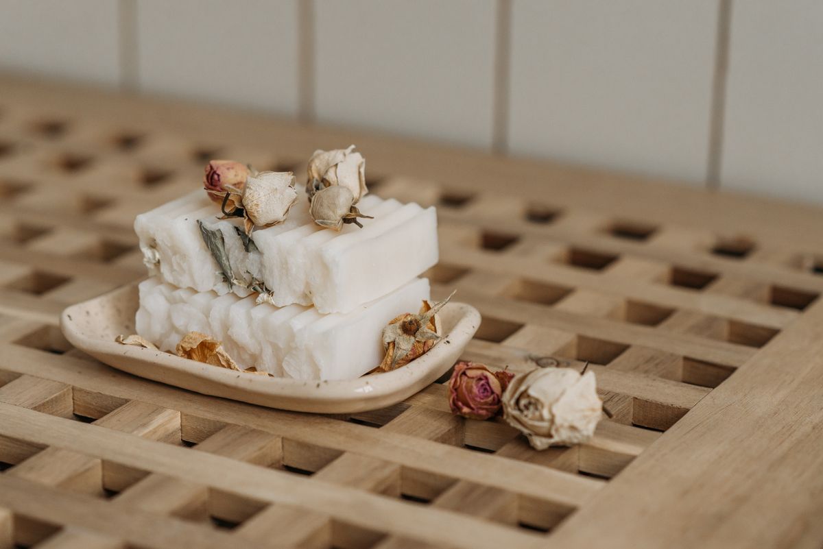 Handmade soap bars with dried roses on a wooden bath tray